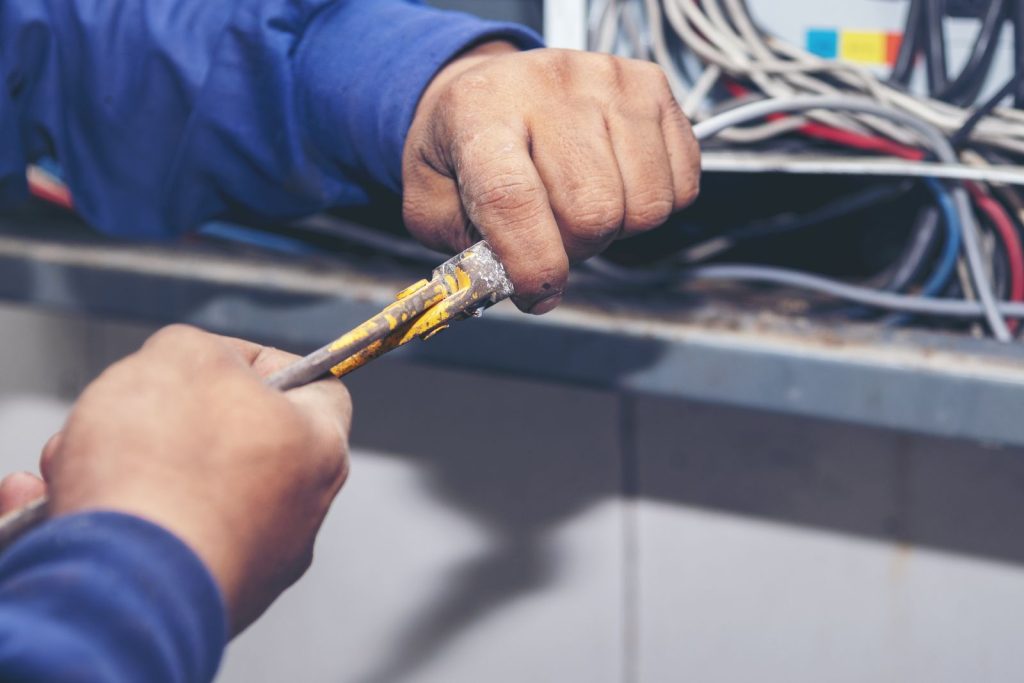 Electrician working on electrical wiring at a workutc