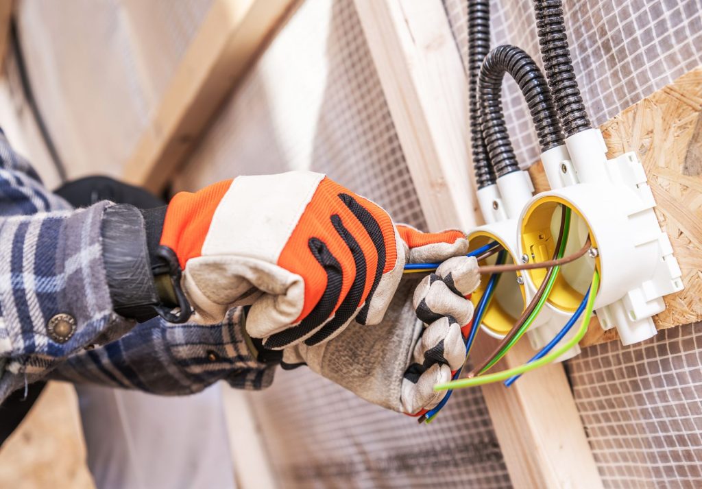 Electrician working on electrical wiring in new houtc