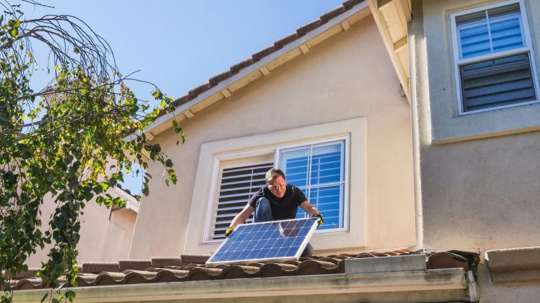 Solar technician installing photovoltaic panels on a sunny rooftop.