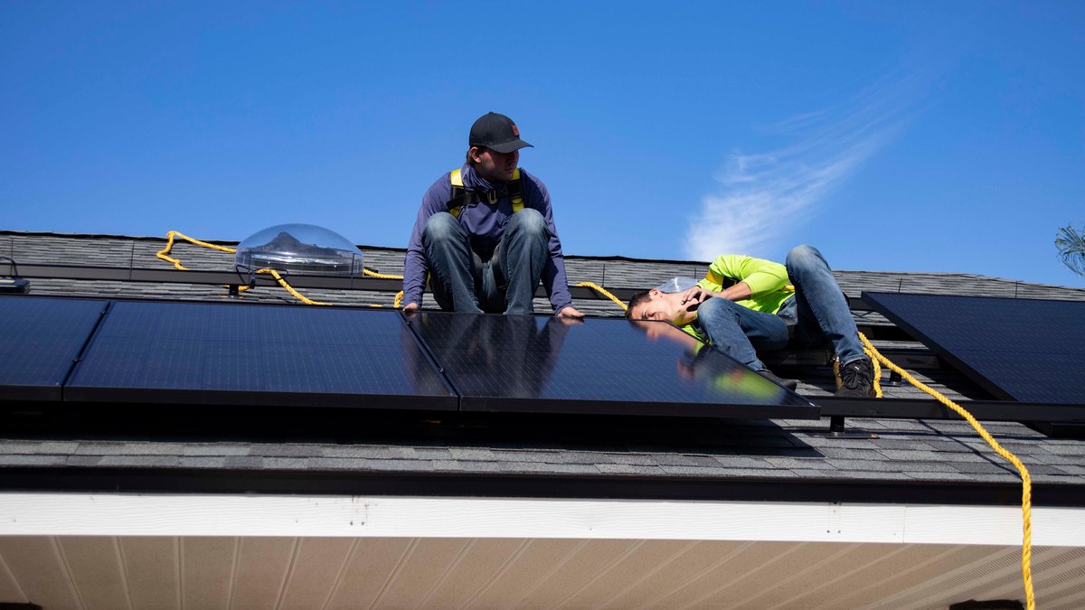 Workers installing solar panels on a roof