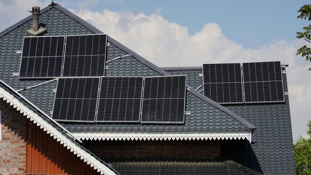 Rooftop solar panels on a house in Srinagar against a blue sky backdrop.