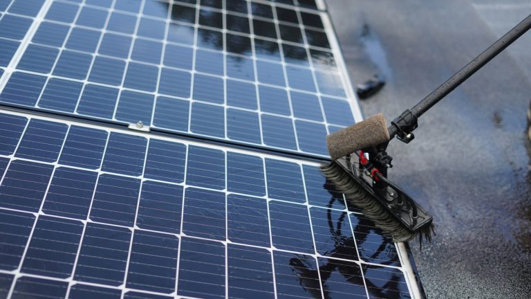 Cleaning solar panels with a long handled brush.