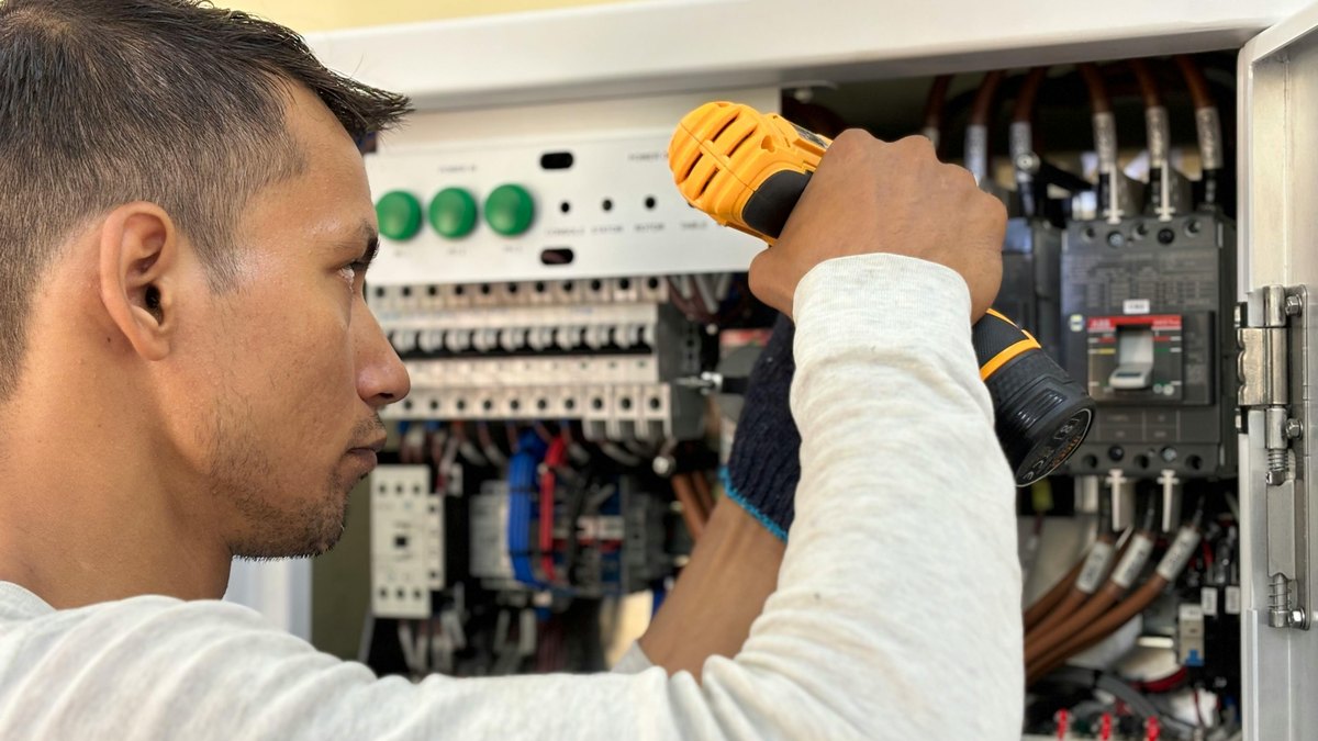 An electrician working on a home circuit breaker panel