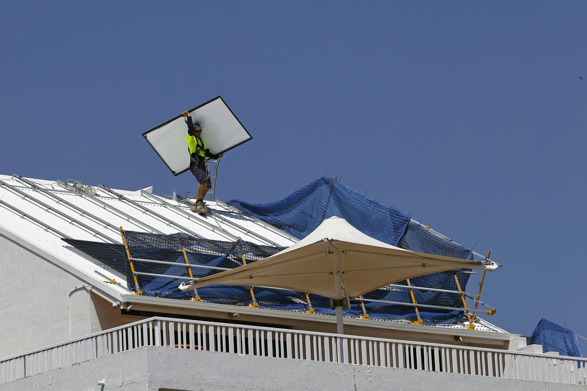 A technician fixing a solar panel on a roof