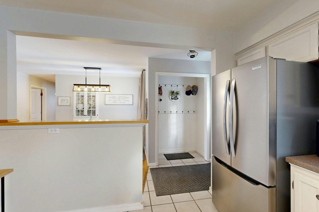 Spacious kitchen with modern design, stainless steel fridge, and elegant lighting.