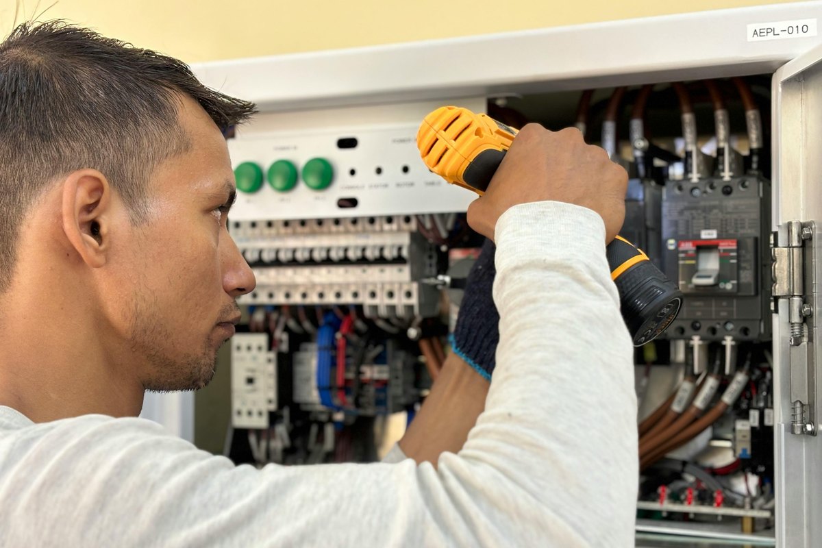 An electrician working at a breaker panel
