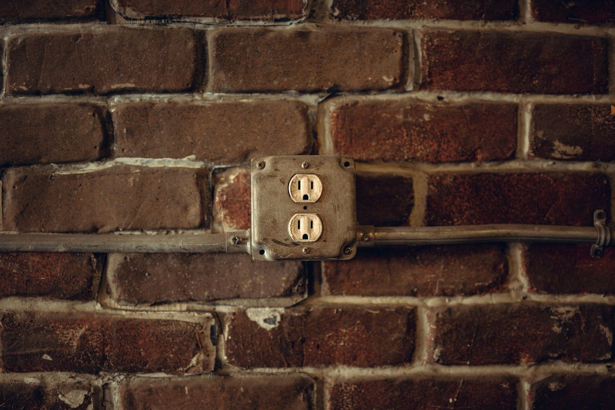 A US-style outlet in a surface box with conduit on a masonry wall