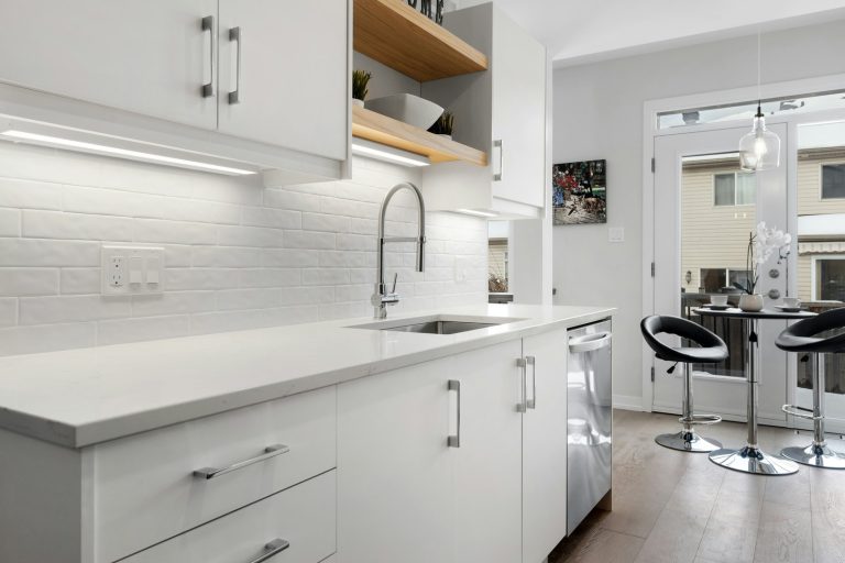 a kitchen with white cabinets and counter tops
