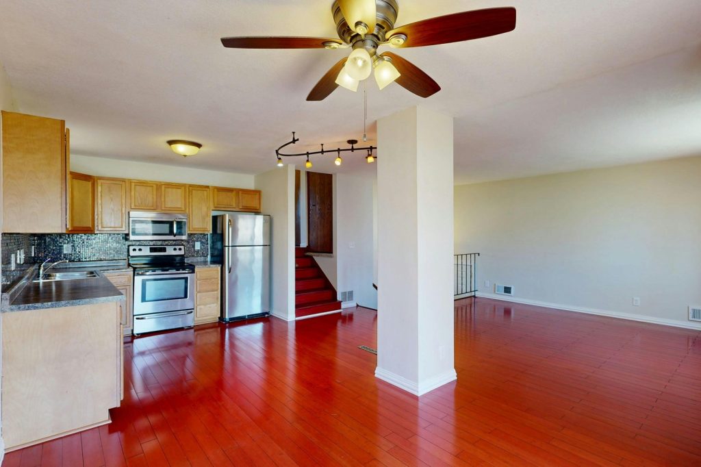 Spacious open-plan kitchen and living room with wood floors and ceiling fan.