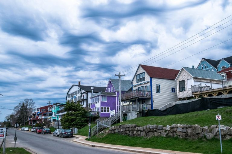 Vibrant homes line a suburban street under a dramatic cloudy sky.