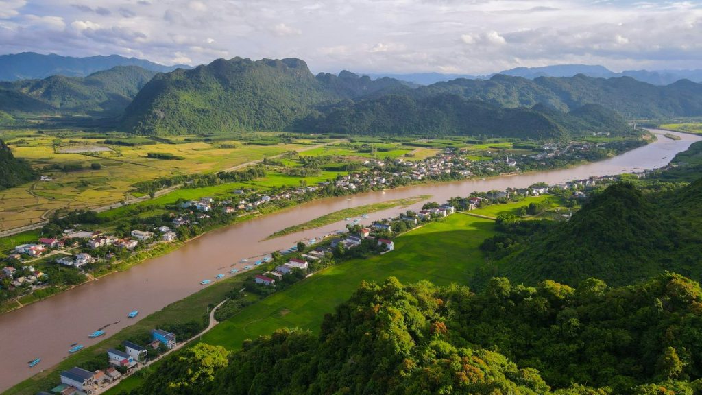 River winding through lush green valley with mountains.