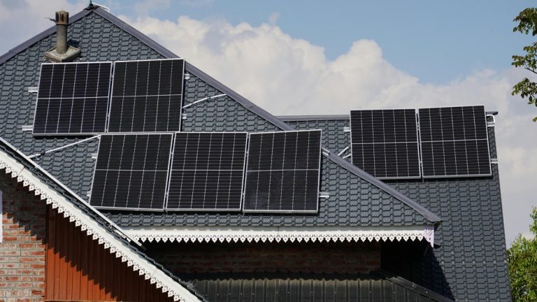 Rooftop solar panels on a house in Srinagar against a blue sky backdrop.