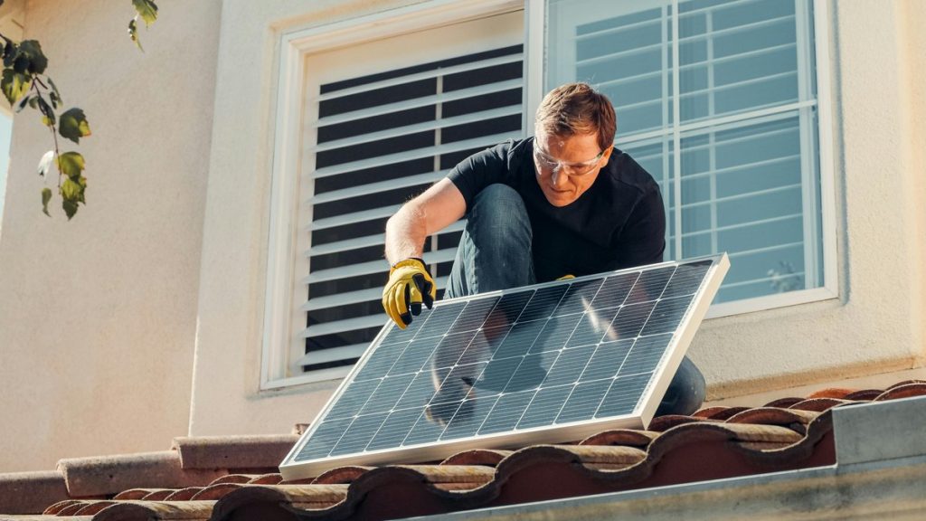 Solar technician installing a photovoltaic panel on a rooftop, promoting renewable energy.